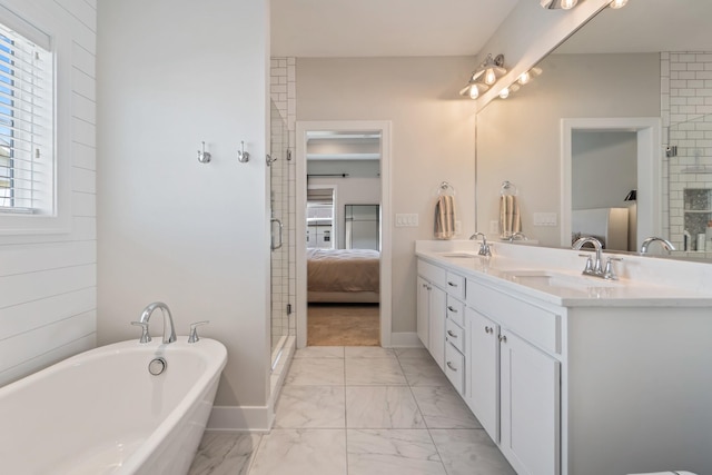 901 Cardinal Dr, Polk City, IA 50226 - ensuite bathroom with marble look tiles, double vanity, a freestanding bath, a stall shower, and baseboards