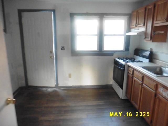 206 S D St, Indianola, IA 50125 - kitchen with exhaust hood, white gas range, dark wood finished floors, a sink, and light countertops