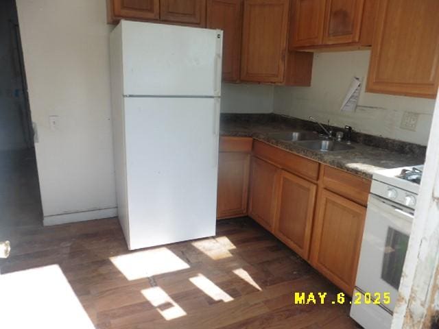410 W 2nd Ave, Indianola, IA 50125 - kitchen with white appliances, a sink, wood finished floors, dark countertops, and brown cabinets