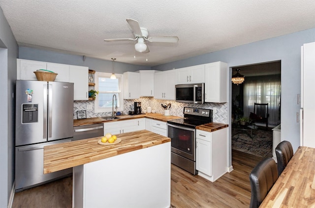 1309 Mccormick St, Des Moines, IA 50316 - kitchen with wood counters, appliances with stainless steel finishes, light wood-style floors, backsplash, and a textured ceiling