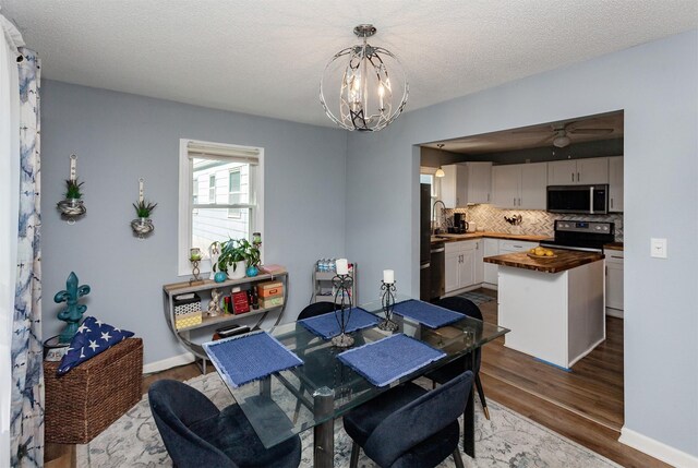 1309 Mccormick St, Des Moines, IA 50316 - dining room with dark wood-style flooring, a chandelier, a ceiling fan, and a textured ceiling