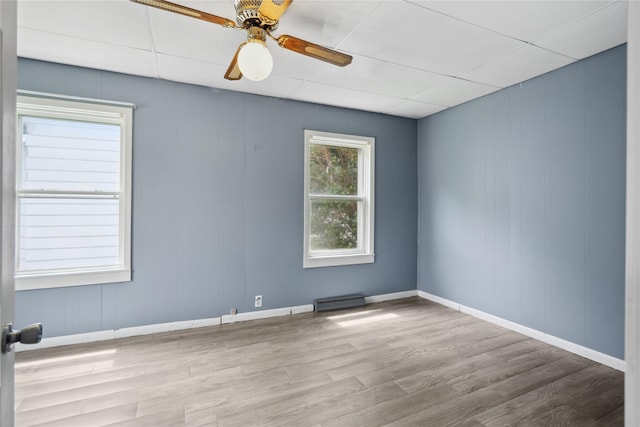 807 Center St, Grinnell, IA 50112 - empty room featuring wood finished floors, baseboards, ceiling fan, and a baseboard heating unit