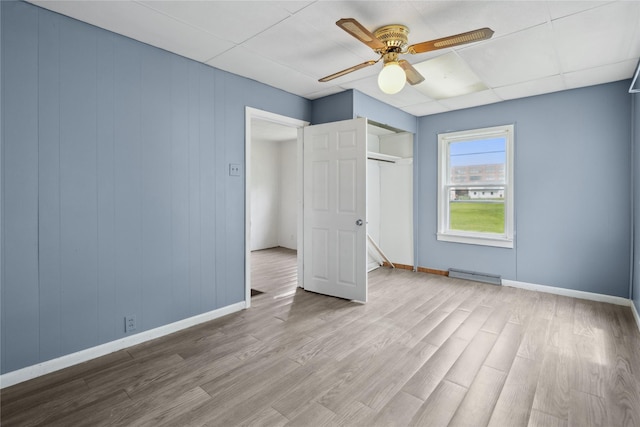 807 Center St, Grinnell, IA 50112 - unfurnished bedroom featuring wood finished floors, baseboards, a baseboard radiator, a closet, and a ceiling fan
