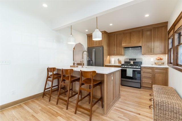 6704 Elmcrest Dr, Windsor Heights, IA 50324 - kitchen featuring stainless steel appliances, tasteful backsplash, a kitchen breakfast bar, light wood finished floors, and recessed lighting