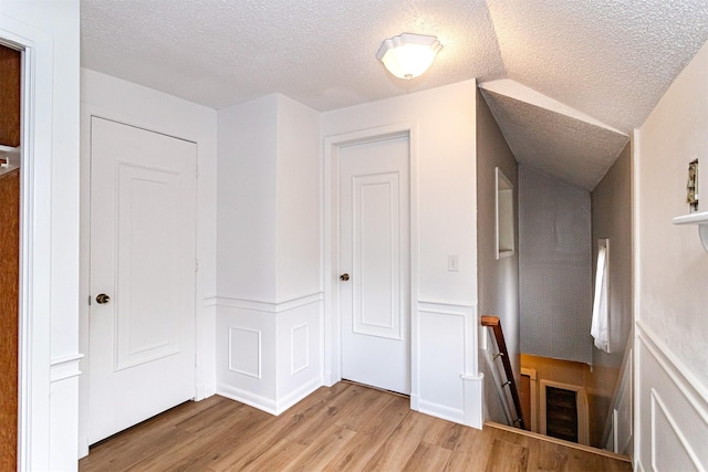 113 N Locust St, Madrid, IA 50156 - hallway featuring a textured ceiling, wood finished floors, and an upstairs landing