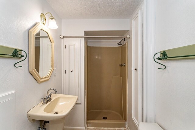 113 N Locust St, Madrid, IA 50156 - bathroom featuring a shower stall, a sink, and a textured ceiling
