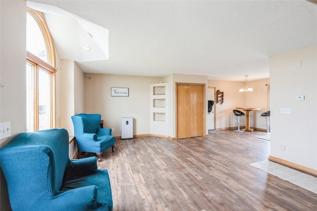 5545 E Douglas Ave, Des Moines, IA 50317 - living area featuring light wood-type flooring, a chandelier, a textured ceiling, and baseboards