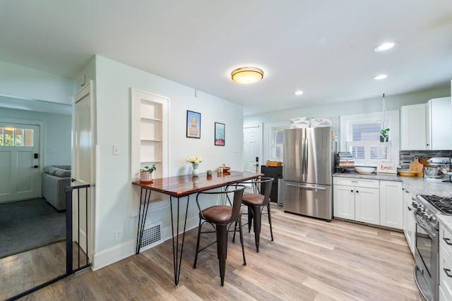 1516 57th Pl, Des Moines, IA 50311 - kitchen featuring stainless steel appliances, light wood-style floors, white cabinetry, recessed lighting, and decorative backsplash