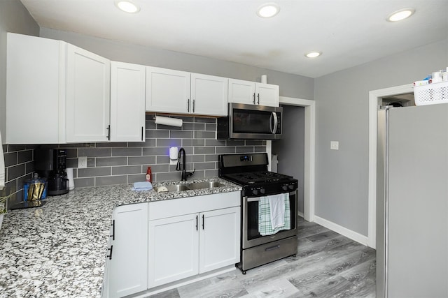 1410 E 21st St, Des Moines, IA 50317 - kitchen with appliances with stainless steel finishes, a sink, white cabinets, backsplash, and recessed lighting