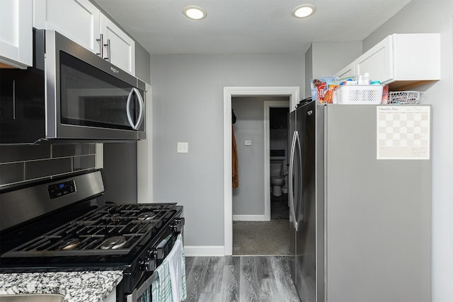 1410 E 21st St, Des Moines, IA 50317 - kitchen with stainless steel appliances, dark wood finished floors, white cabinetry, baseboards, and recessed lighting