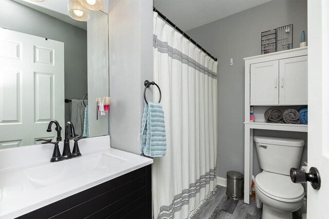 1410 E 21st St, Des Moines, IA 50317 - bathroom featuring toilet, vanity, wood finished floors, a shower with curtain, and baseboards