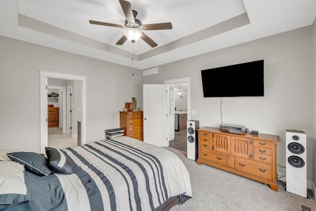 3911 NW 14th Ct, Ankeny, IA 50023 - bedroom featuring a raised ceiling, light carpet, ensuite bathroom, and a ceiling fan