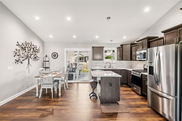 2320 SE Maxwell Dr, Waukee, IA 50263 - kitchen featuring stainless steel appliances, a center island, dark brown cabinetry, decorative backsplash, and lofted ceiling