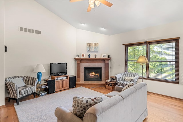 6814 Aubrey Ct, Johnston, IA 50131 - living area featuring vaulted ceiling, light wood-style floors, a ceiling fan, a tile fireplace, and baseboards