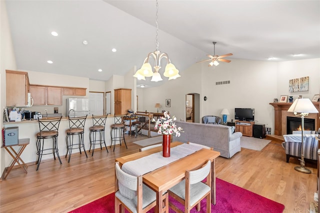 6814 Aubrey Ct, Johnston, IA 50131 - dining area featuring ceiling fan, arched walkways, high vaulted ceiling, light wood-style floors, and a glass covered fireplace