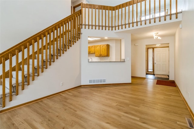 4400 Ep True Pkwy Unit 4, West Des Moines, IA 50265 - unfurnished living room featuring light wood-type flooring, baseboards, stairs, and a high ceiling