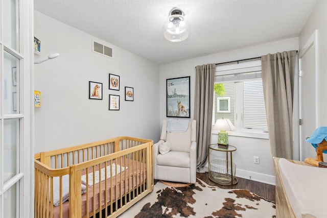 4670 Meadow Valley Dr, West Des Moines, IA 50265 - bedroom with wood finished floors, a nursery area, a textured ceiling, and baseboards