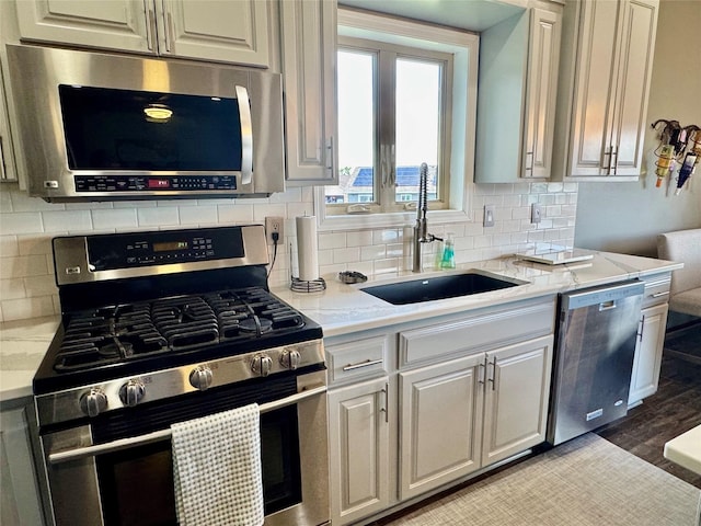 1008 Pine Brooke Ct, Clear Lake, IA 50428 - kitchen with stainless steel appliances, a sink, backsplash, and light stone counters