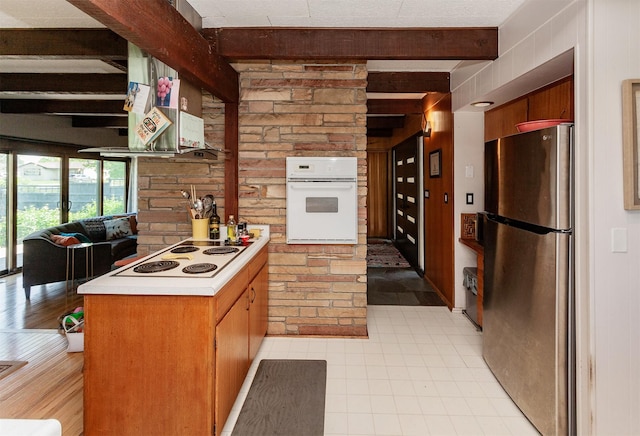 201 Jet St SW, Mitchellville, IA 50169 - kitchen with white appliances, beamed ceiling, a peninsula, light countertops, and brick wall