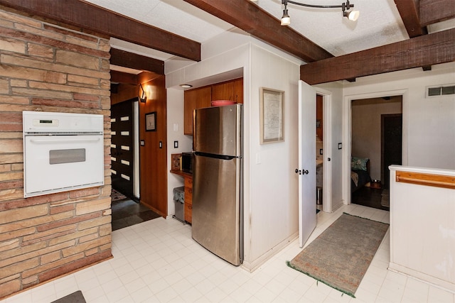 201 Jet St SW, Mitchellville, IA 50169 - kitchen featuring freestanding refrigerator, white oven, beam ceiling, wooden walls, and light tile patterned floors