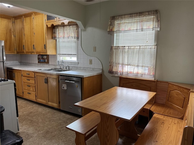 1300 Shawnee Ave, Des Moines, IA 50313 - kitchen featuring stainless steel appliances, a sink, decorative backsplash, and brown cabinetry