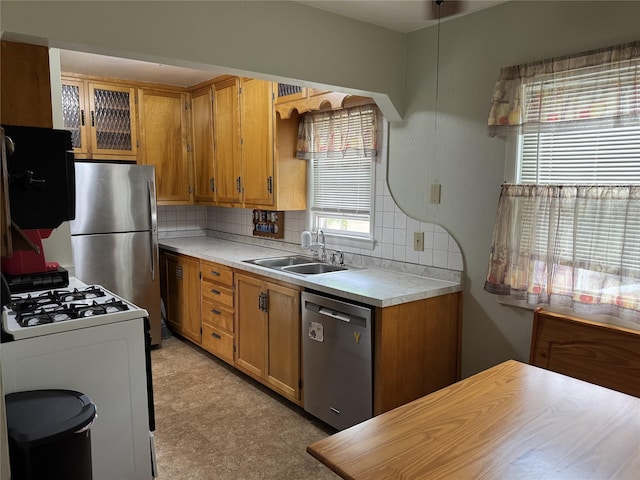 1300 Shawnee Ave, Des Moines, IA 50313 - kitchen with appliances with stainless steel finishes, light countertops, decorative backsplash, brown cabinetry, and a sink