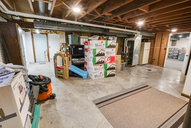216 E 9th St, Pella, IA 50219 - unfinished basement featuring freestanding refrigerator and heating unit