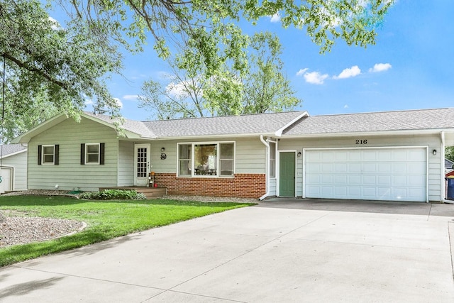216 E 9th St, Pella, IA 50219 - single story home featuring an attached garage, concrete driveway, a front yard, brick siding, and a shingled roof