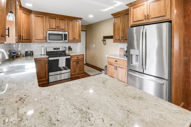 216 E 9th St, Pella, IA 50219 - kitchen featuring stainless steel appliances, a sink, light stone countertops, baseboards, and backsplash
