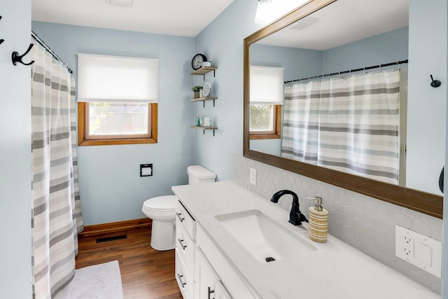 216 E 9th St, Pella, IA 50219 - full bathroom with tasteful backsplash, vanity, wood finished floors, toilet, and baseboards