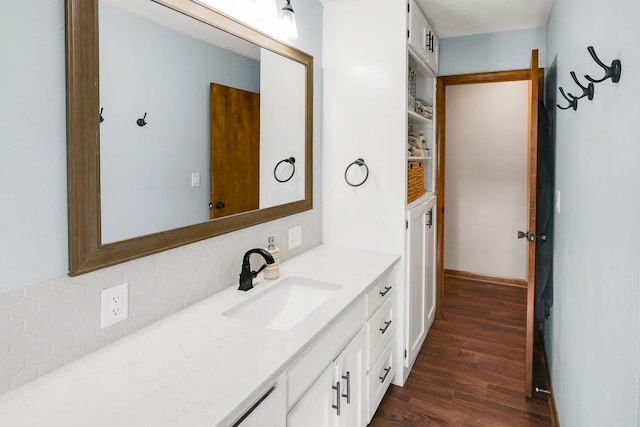 216 E 9th St, Pella, IA 50219 - bathroom featuring vanity, wood finished floors, and tasteful backsplash