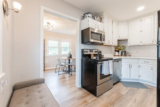 6100 College Ave, Des Moines, IA 50322 - kitchen featuring appliances with stainless steel finishes, white cabinetry, light countertops, light wood-type flooring, and decorative backsplash