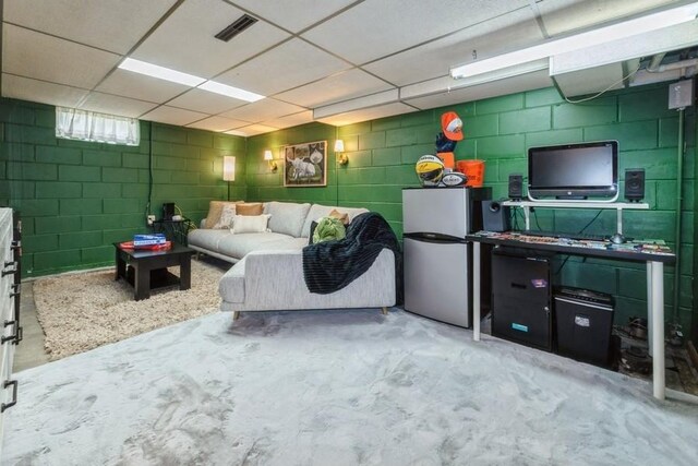 6100 College Ave, Des Moines, IA 50322 - living room featuring concrete block wall, concrete floors, and a paneled ceiling