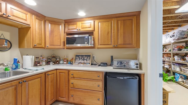 510 Lexington Dr, Clear Lake, IA 50428 - kitchen featuring stainless steel microwave, refrigerator, a sink, light countertops, and brown cabinetry