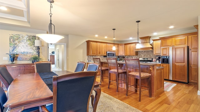 510 Lexington Dr, Clear Lake, IA 50428 - kitchen with custom exhaust hood, stainless steel appliances, light wood-style flooring, tasteful backsplash, and a breakfast bar