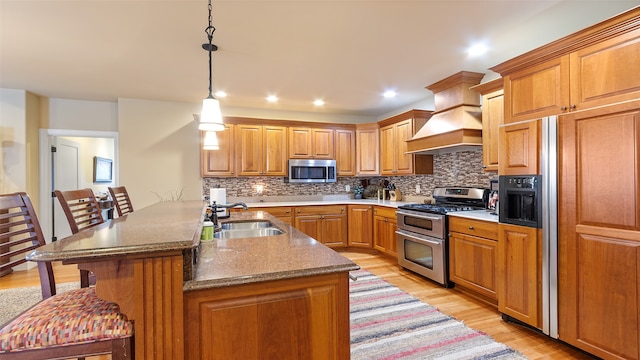 510 Lexington Dr, Clear Lake, IA 50428 - kitchen with stainless steel appliances, a sink, light wood-style flooring, a kitchen breakfast bar, and tasteful backsplash