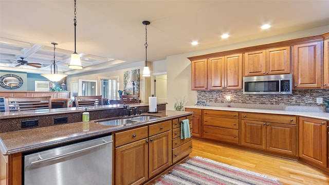 510 Lexington Dr, Clear Lake, IA 50428 - kitchen with stainless steel appliances, a sink, brown cabinets, light wood-style flooring, and backsplash