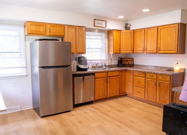 2326 E 39th Ct, Des Moines, IA 50317 - kitchen with appliances with stainless steel finishes, a sink, brown cabinetry, light wood-type flooring, and recessed lighting
