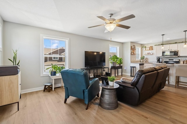 247 Red Oak Ct, Norwalk, IA 50211 - living area featuring light wood-style flooring, a ceiling fan, and baseboards