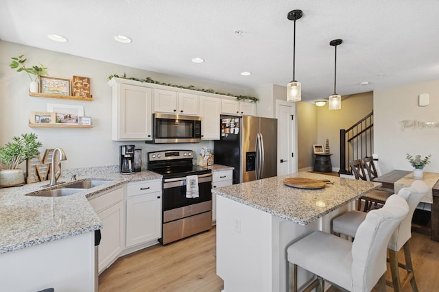 247 Red Oak Ct, Norwalk, IA 50211 - kitchen featuring stainless steel appliances, a sink, light wood-style floors, white cabinets, and recessed lighting