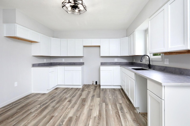 314 E Front St, Colfax, IA 50054 - kitchen with a sink, light wood-style floors, white cabinets, and baseboards