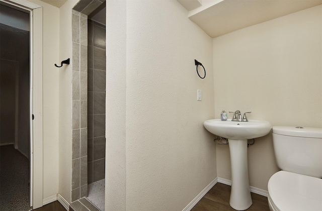 2112 E 23rd St, Des Moines, IA 50317 - bathroom featuring toilet, tiled shower, baseboards, and wood finished floors