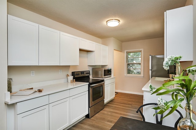 2112 E 23rd St, Des Moines, IA 50317 - kitchen featuring stainless steel appliances, white cabinets, light wood-style flooring, light countertops, and baseboards