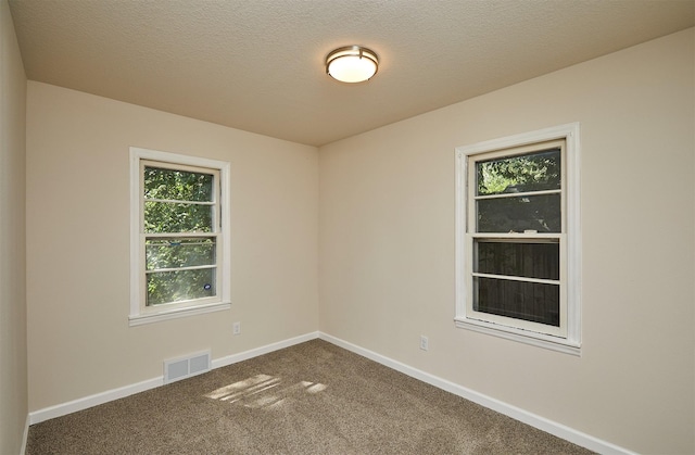 2112 E 23rd St, Des Moines, IA 50317 - unfurnished room featuring healthy amount of natural light, dark colored carpet, baseboards, and a textured ceiling