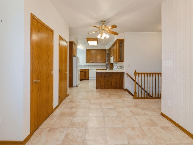 2117 W 4th Ave, Indianola, IA 50125 - kitchen featuring white appliances, brown cabinetry, a peninsula, a ceiling fan, and light countertops