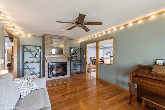 529 NW State St, Ankeny, IA 50023 - living room featuring a brick fireplace, a ceiling fan, wood finished floors, and baseboards