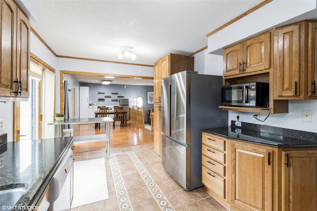 529 NW State St, Ankeny, IA 50023 - kitchen with freestanding refrigerator, light tile patterned flooring, crown molding, dark stone counters, and brown cabinets
