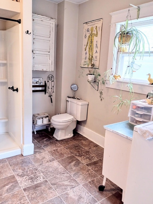 318 W Green St, Winterset, IA 50273 - bathroom featuring baseboards, a stall shower, and toilet
