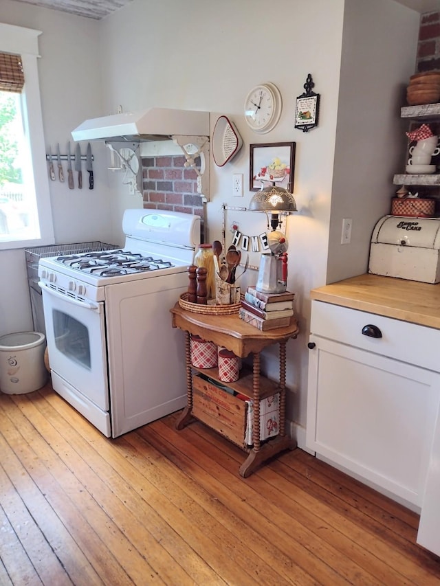 318 W Green St, Winterset, IA 50273 - kitchen with white gas range, light wood-style floors, and white cabinets