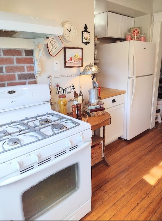 318 W Green St, Winterset, IA 50273 - kitchen featuring white appliances, light wood finished floors, white cabinets, and under cabinet range hood